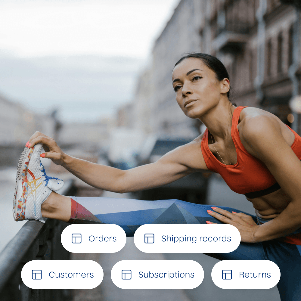 A photograph of a person stretching with a list of example data tables overlayed. The data tables included are for orders, shipping records, customers, subscriptions, and returns.